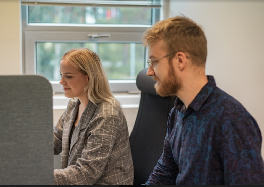 Ohjelmoinnin valmentaja opastamassa Buutin ohjelmointikoulutuksen osallistujaa ohjelmointitehtävän tekemisessä